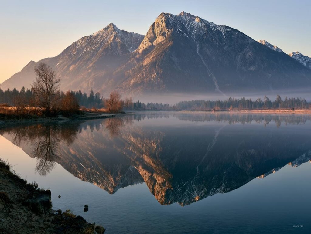 Snijeg okriveni planinski vrh reflektovan u mirnom alpskom jezeru