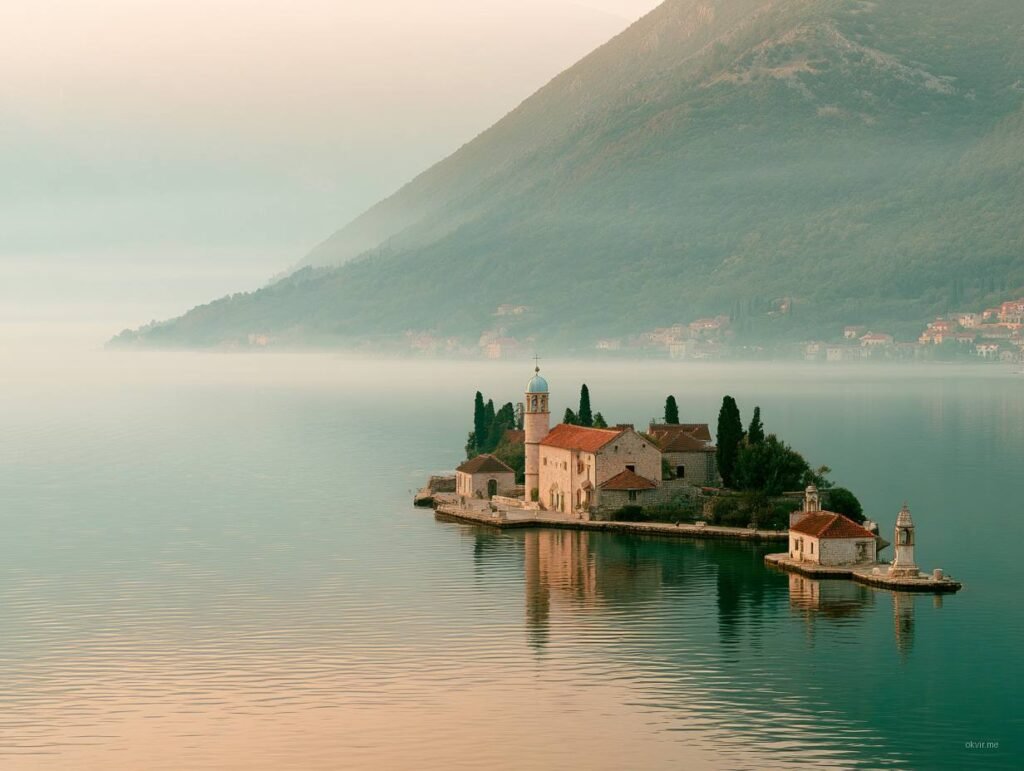 Kameni manastir na ostrvici u mirnom moru sa planinom