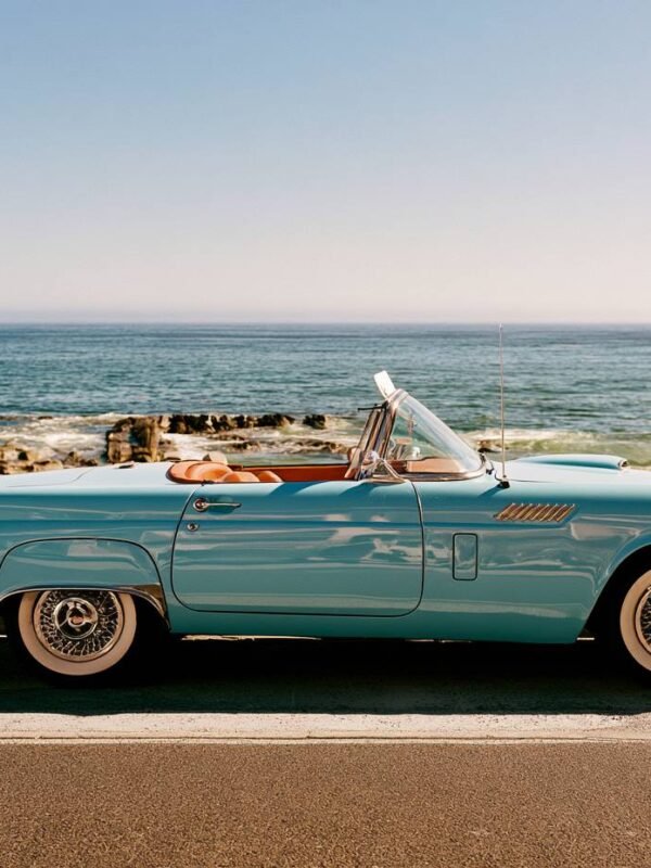 Turquoise kabriolet parkiran na priobalnoj cesti pored mora